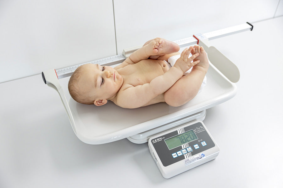 Baby lying on a baby scale with measuring rod.